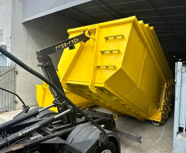 RapidPolk Dumpster Rental unloads a roll-off dumpster with a hook-lift system at a service facility