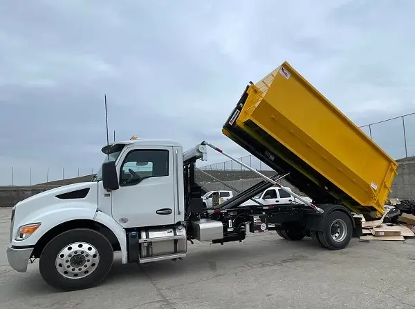 RapidPolk Dumpster Rental roll off truck unloading a yellow container at a job site
