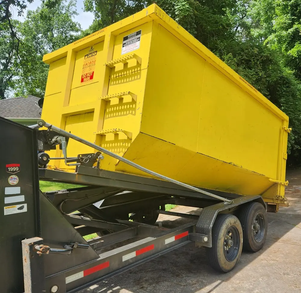 RapidPolk Dumpster Rental yellow dumpster being lowered onto customer’s driveway for cleanout service